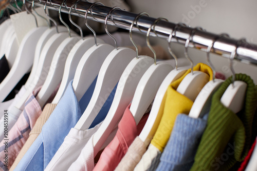 Canvas Print Clothing items neatly organized on white wooden hangers on a metal rack, showing