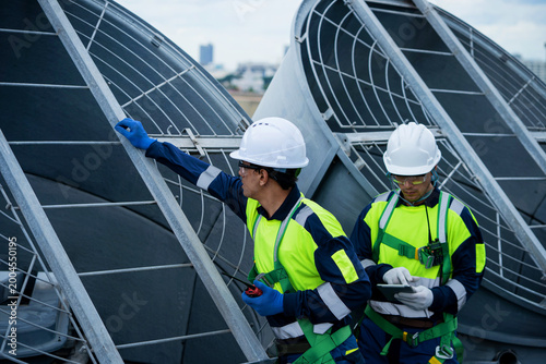 Bilde på lerret Two professional engineers are inspecting solar panels on the roof of a large factory