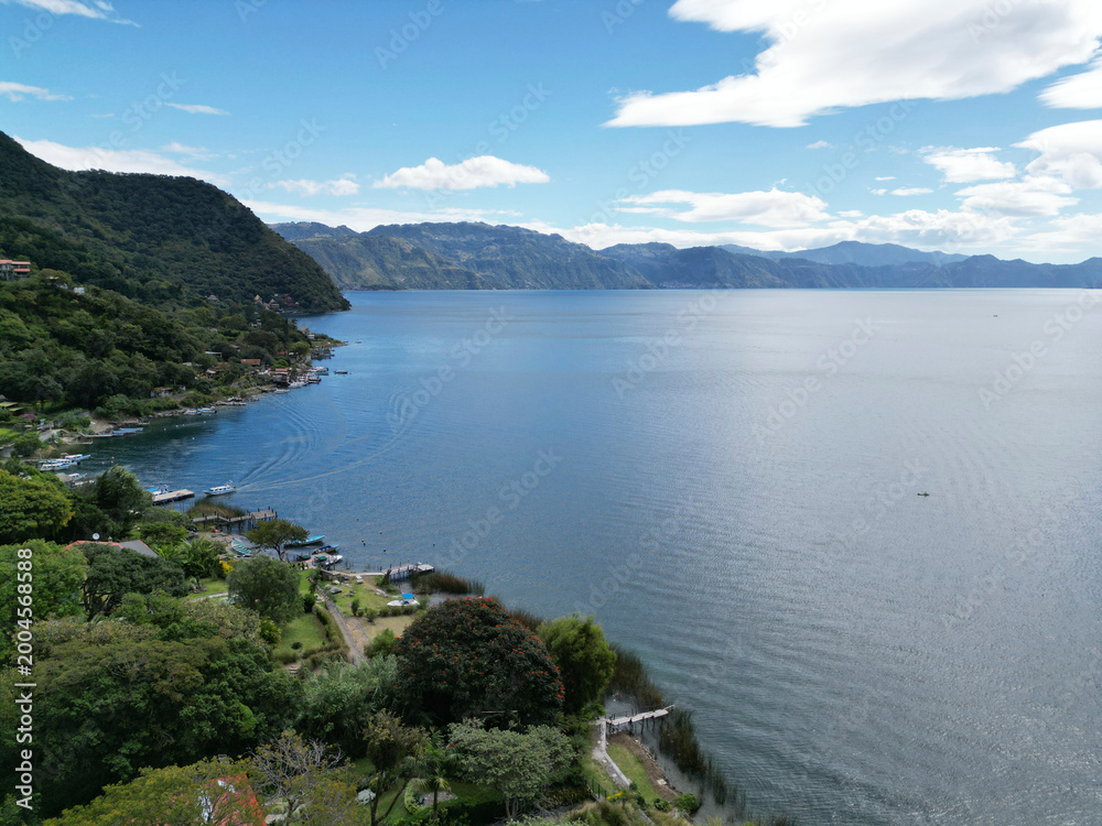 Obraz premium aerial view of lake atitlan with ferry boats in the water guatemala volcano vulcanic mountains volcanoes crater beautiful travel tourism destination latin america ferry port dock shore serene water
