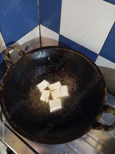 Frying Tofu in Traditional Wok on Home Kitchen Stove