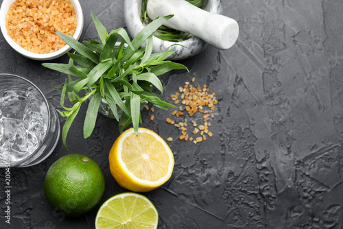 Cuadro en lienzo Mortar with pestle and ingredients for estragon lemonade on black table, flat lay