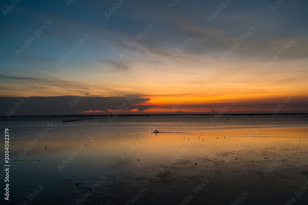 Fototapeta premium Fiery orange sunset over calm ocean horizon, peaceful seascape