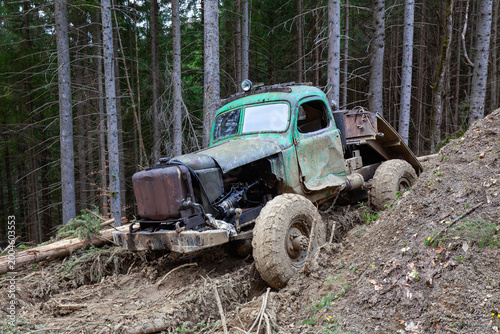 Abandoned and rusty vintage military truck used for logging in a dense forest.