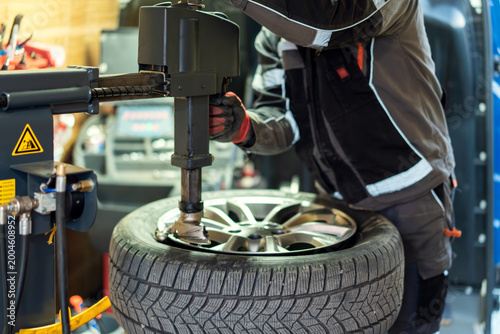 Cuadro en lienzo Mechanic works on a tire at an auto repair shop during the day