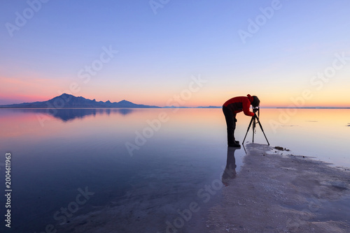 Mystical morning glow with a photographer on the shallow water, Bonneville Salt Flats near Great Salt Lake, Utah