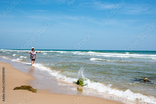 Картината върху платно Mujer en la playa con los brazos abiertos.