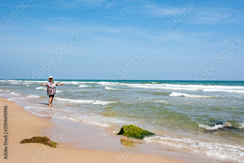 Fotografie Mujer en la playa con los brazos abiertos.