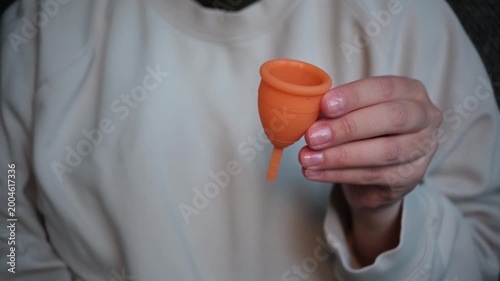 Woman holding reusable menstrual cup promoting sustainable hygiene product