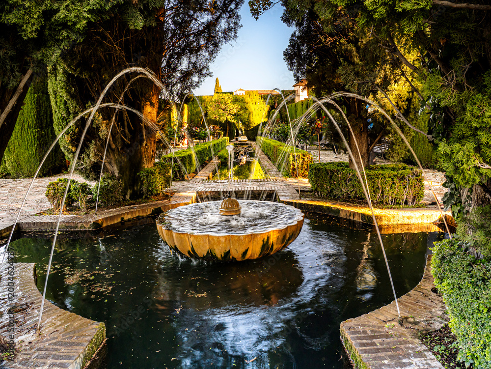 Fototapeta premium Ornate Stone Fountain in Alhambra Generalife Gardens With Arched Water Jets at Sunset, Granada