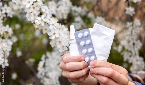Canvastavla Child holding nasal spray, pills and tissue against a blooming tree