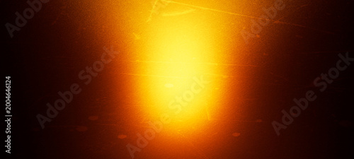 Obraz na plátně Warm, glowing orange light with a bright yellow center illuminates a dark, textured background with scratches, creating a vintage, cinematic, and ethereal atmosphere