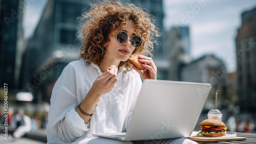 Freelancer enjoying lunch outdoors while focused on work at a cafe