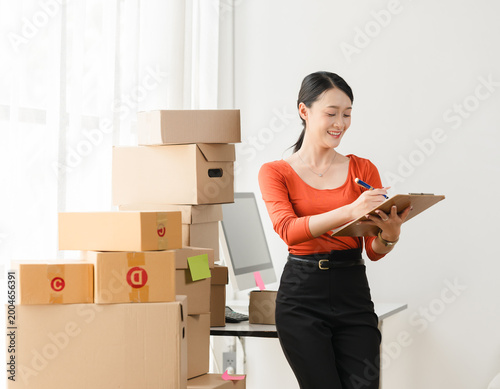 Startup small business entrepreneur or freelance Asian woman using a laptop with box, Young success Asian woman with her hand lift up, online marketing packaging box and delivery, SME concept