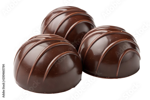 Three round dark chocolate truffles with decorative lines arranged in a small group