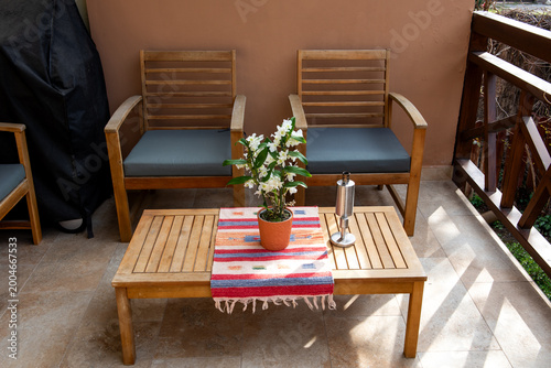 Cozy wooden balcony seating with table and decorative plant