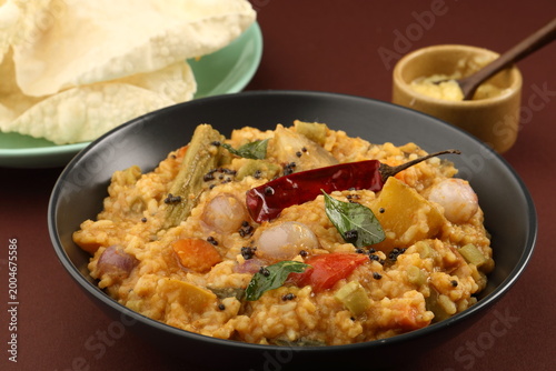 Traditional Tamil Nadu Sambar rice with mixed vegetables, dal, rice and served with ghee and Appalam