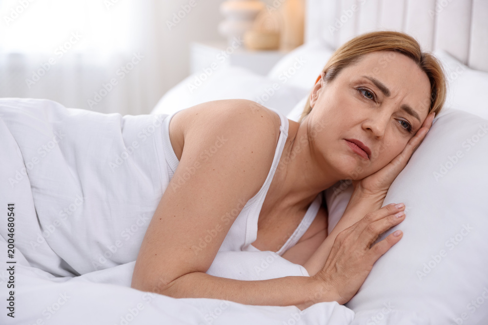 Obraz premium Menopause. Upset woman lying in bed at home
