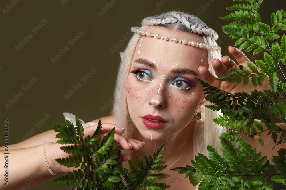 Fototapeta premium Beautiful elf girl with floral decor on dark olive background