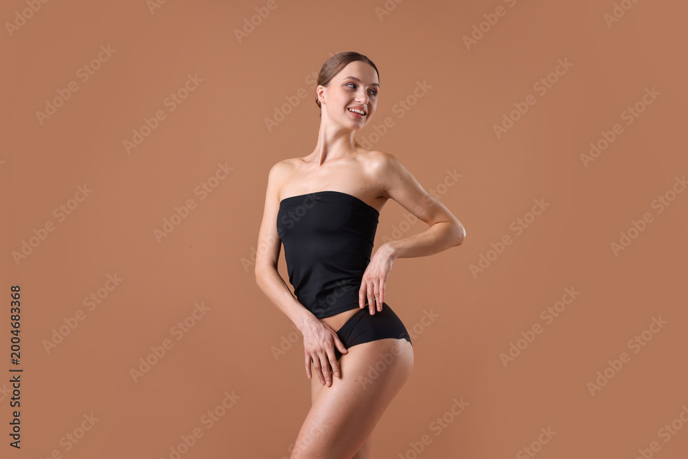 Obraz premium Smiling woman in underwear with slim body on beige background