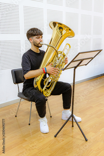 Young man sitting playing a tuba in F