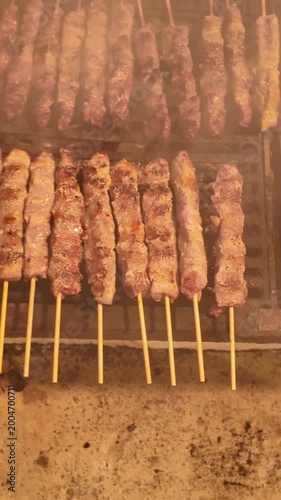 View of a vertical footage of the greek meat dish Souvlaki cooked on long skewer over a charcoal barbecue