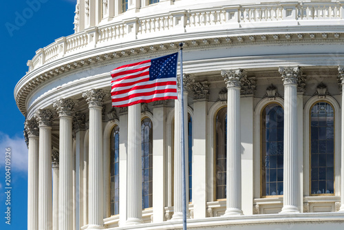 Fotografie US Capitol dome with American flag and blue sky in Washington DC government land
