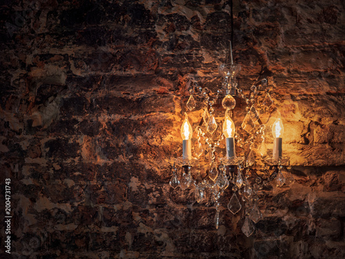 Vintage chandelier lighting a rustic brick wall background