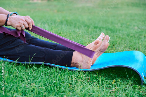 Mature woman stretching with a resistance band and toe separators