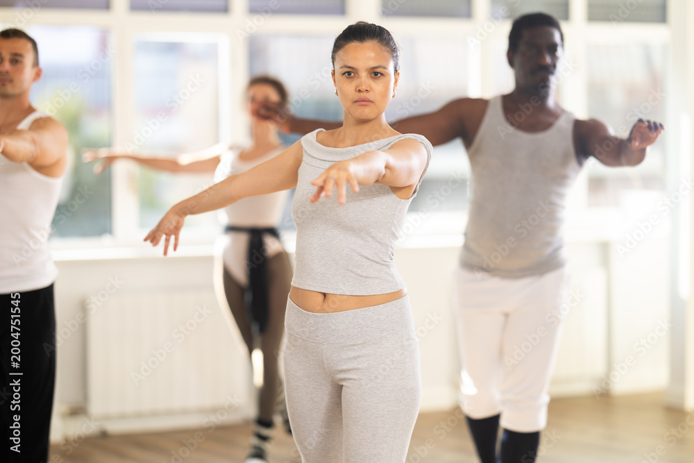 Fototapeta premium Concentrated women and men rehearsing ballet dance in studio
