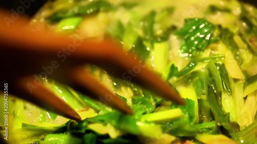 Cooking wild leek asphodelus greens in pan. Macro shot of traditional healthy vegetarian meal preparation using fresh seasonal mountain herbs for rustic culinary content