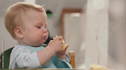 Happy baby holds pieces of bread, radiating joy and innocence. This video exudes innocence and is perfect for food and child-related topics