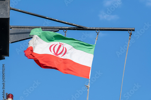 Iranian flag on the mast on vessel. Flag of Iran on ship. Iranian ensign. Iran flag on ship mast against blue sky. Maritime industry, shipping, geopolitics, sanctions, Strait of Hormuz, international 