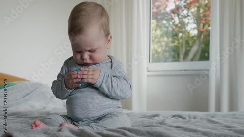 Infant studies toy. Young child carefully examines blue ball. Infant attentively inspects textured toys in comfortable environment, in a soft, warm, and inviting atmosphere