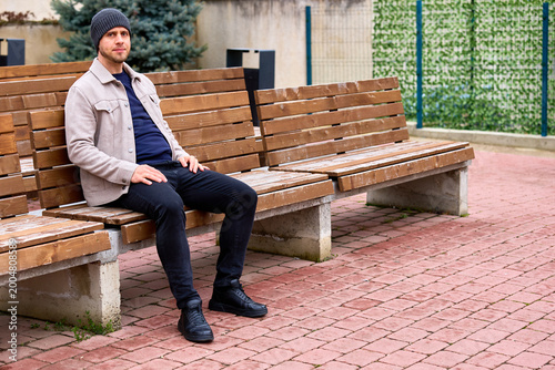 Man sits calmly on outdoor wooden bench