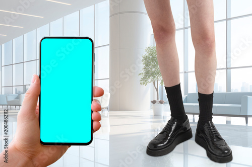 Creative surreal business lifestyle scene featuring a hand holding a smartphone with copy space screen inside a modern corporate interior, combined with fashion styling and oversized perspective