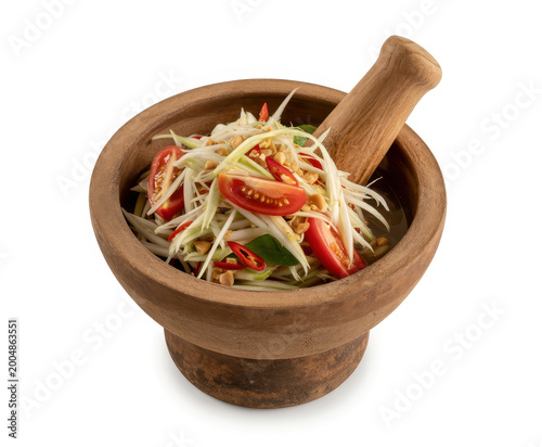 Traditional thai green papaya salad in a wooden mortar and pestle on a white background