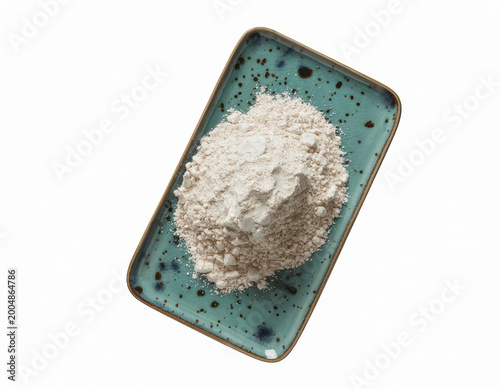 A pile of white flour on a small rectangular turquoise ceramic plate with dark speckles pattern