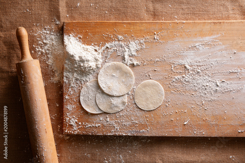 Cuadro en lienzo Top View of Homemade Dumpling Dough Circles with Rolling Pin and Flour on Wooden