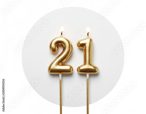 Two gold birthday candles shaped as the number twenty-one with lit flames on white background