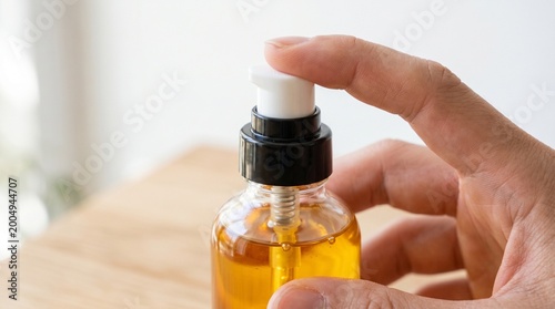 Cuadro en lienzo hand dispensing golden liquid from amber dropper bottle on wooden surface