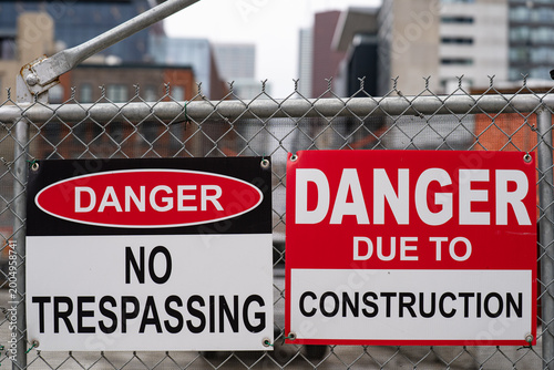 Fotografija Danger no trespassing and construction warning signs on metal fence