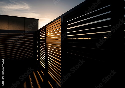 Sunset light shining through modern wooden slatted fence with sunburst