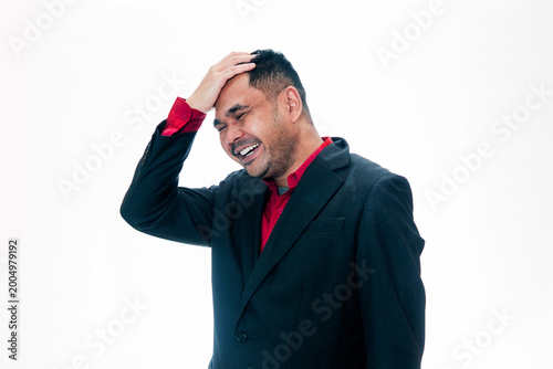 Fotografi Portrait of a joyful man in a black suit and red shirt laughing while touching h