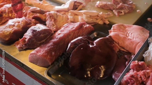 Butcher stall showing assorted raw meat cuts including pork beef and offal arranged on counter at market. Fresh meat selection concept