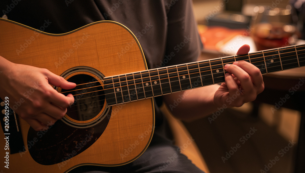 Fototapeta premium やわらかな光の中で弦を奏でる日本人ギタリストの手元写真