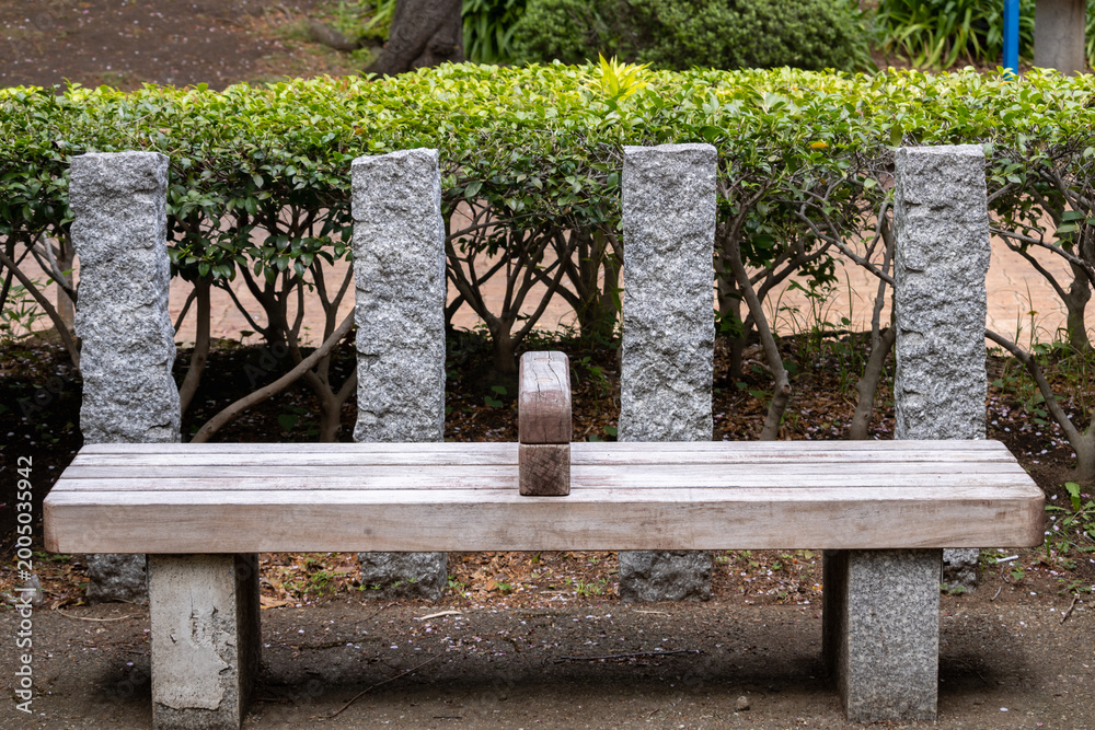 Naklejka premium empty wooden park bench with stone supports outdoors