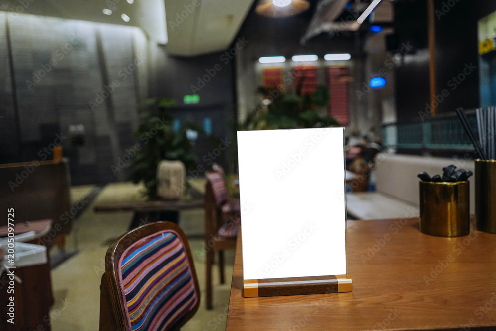 Obraz premium Mock up Menu frame standing on wood table in Bar restaurant cafe. space for text.