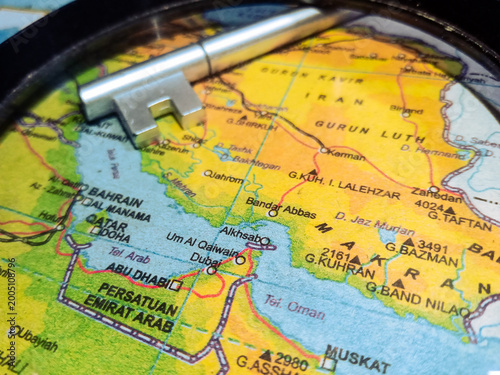 Silver metal key placed on a map of United Arab Emirates, Qatar, and Iran.