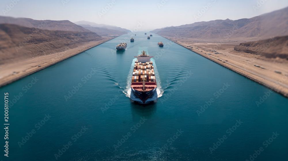 Fototapeta premium Impressive Container Ship Convoy Traversing a Vital Man-Made Canal Between Vast Desert Landscapes