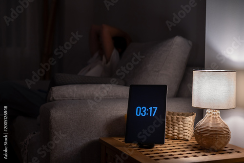 Bild auf Leinwand Person lying awake in couch in a dark room during the early hours, experiencing